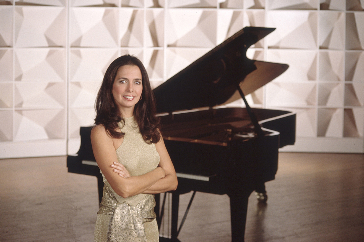 a portrait of clara rodriguez with a piano behind her